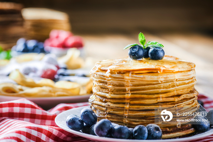 Fresh delicious pancakes with honey leak. Heap of fresh pancakes with blueberries.