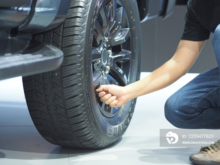 Man hand cheking big wheel of new car