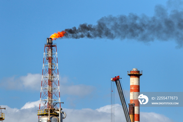 Flames and black smoke emerge from the torches of a refinery. Environmental pollution