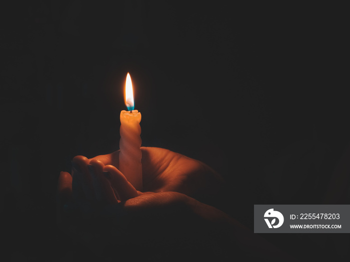 Burning candle in male hand on a black background