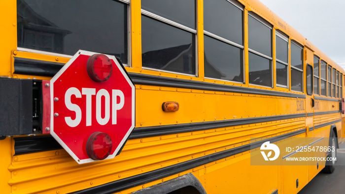 Panorama Exterior view of a yellow school bus with a red stop sign and signal lights