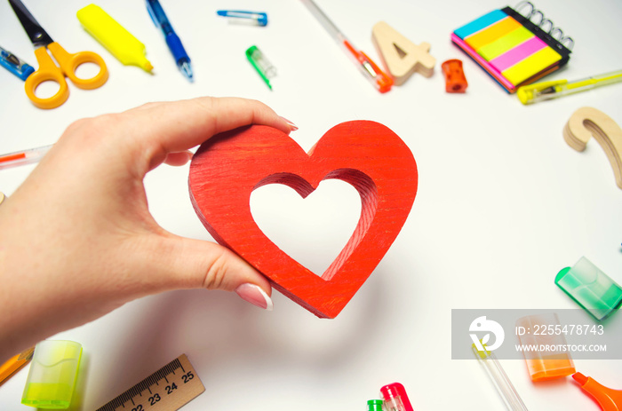 I Love School! the student holds the heart in his hands on the background of the desk. love of learning. stationery. back to school. education. teenage first school love.