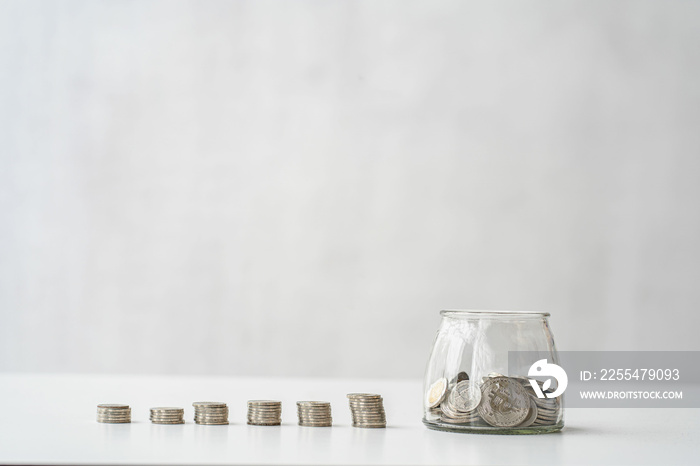 Save money. Personal finance planning and savings concept with piggy bank next to pile of coins on gray background.
