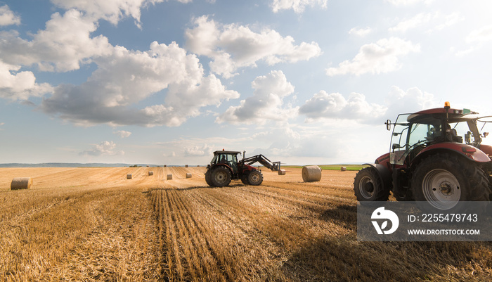 A tractor collecting straw bales