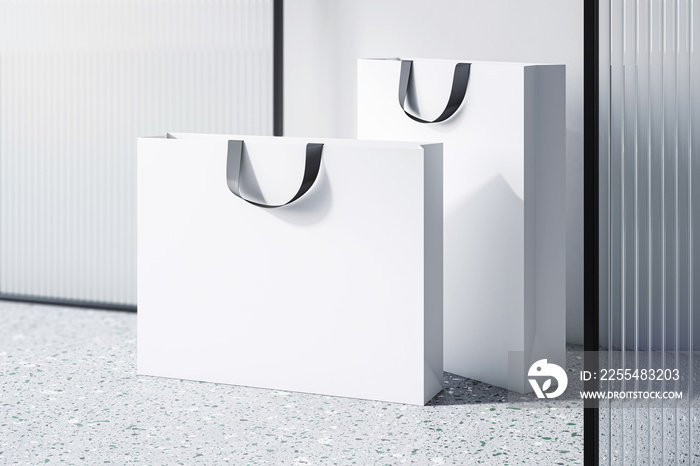 Perspective view on blank white paper shopping bags with place for your brand name or text on concrete floor near decorative partition and light wall background, close up. 3D rendering, mockup