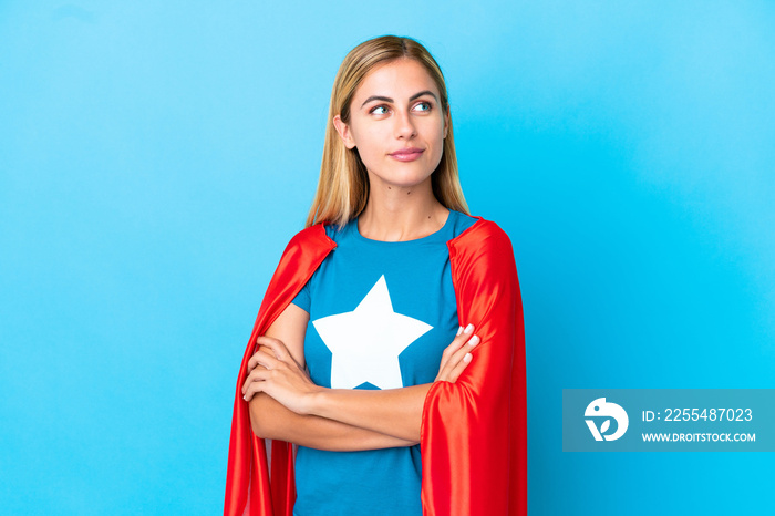 Blonde woman over isolated background in superhero costume with arms crossed