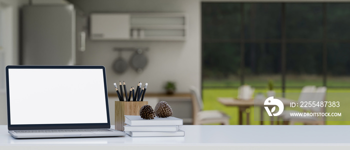 Laptop mockup and copy space on white tabletop over blurred kitchen in background. close-up