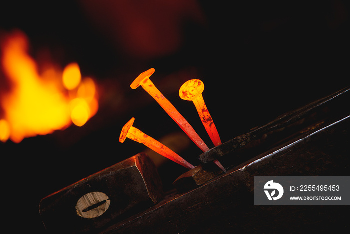 Close-up hot metal nail for horseshoes on an anvil in blacksmith’s workshop