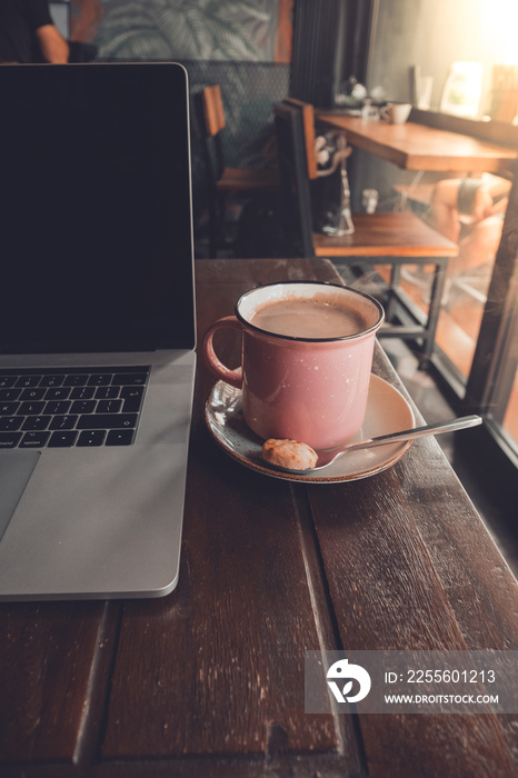 Nómada digital trabajando en una cafetería con su ordenador y un café