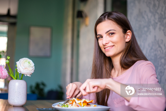 Cheerful smiling young woman looking at camera while taking her lunch