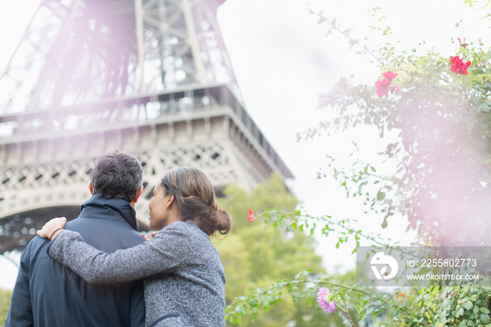 Affectionate couple standing below Eiffel Tower, Paris, France