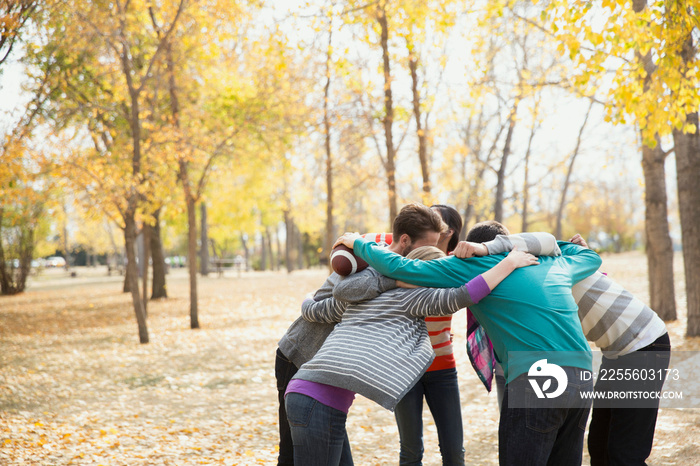 Group of friends forming huddle while playing American football