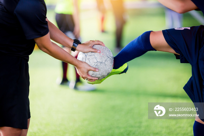 young boy soccer player kick ball in hands of coach