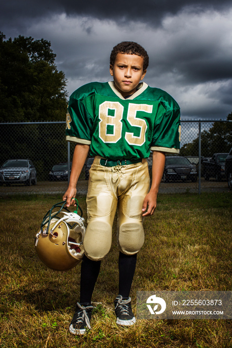 Portrait of boy with helmet standing in field at dusk