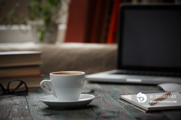 A cup of coffee in the workplace on a wooden table.