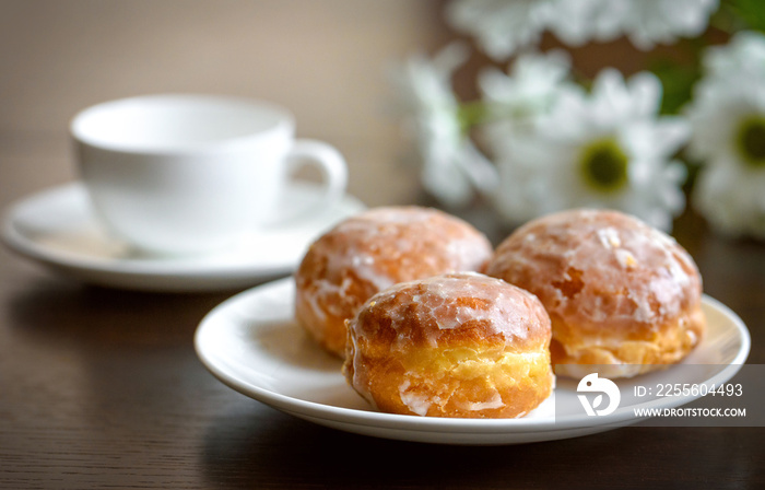 Donuts on a white plate with flower on the table