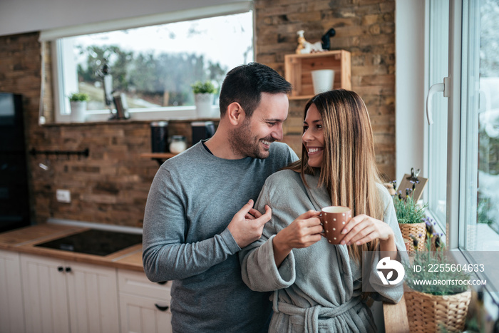 Portrait of a happy couple drinking coffee in the morning in the kitchen at home.