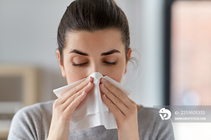 healthcare, cold, allergy and people concept - close up of sick woman blowing her runny nose in pape