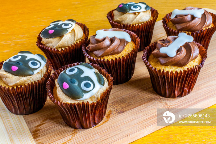 A selection of dog themed cupcakes on a wooden platter