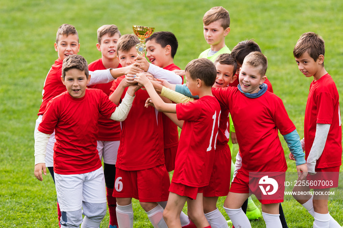 Kids soccer football - children players celebrating with a trophy after match on soccer field