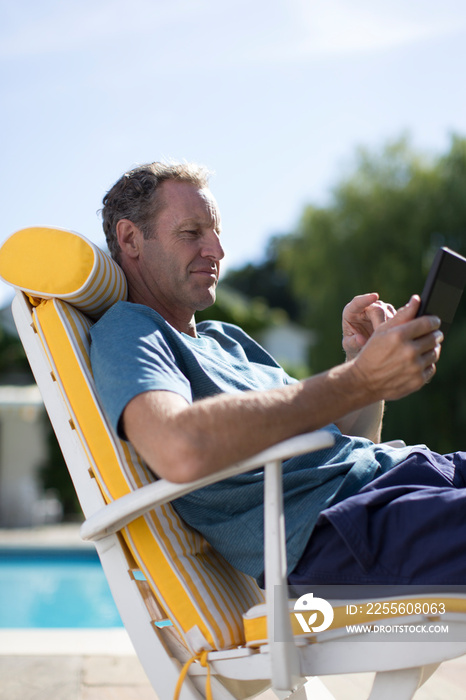 Mature man using smart phone on sunny patio