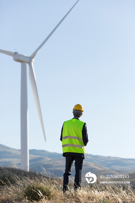 Engineer examining wind turbine on sunny wind farm