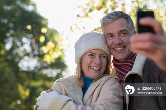 Happy mature couple taking selfie with smart phone in park