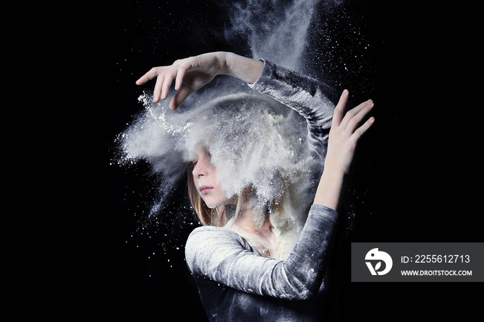 Little cute girl dancing with white powder on black background