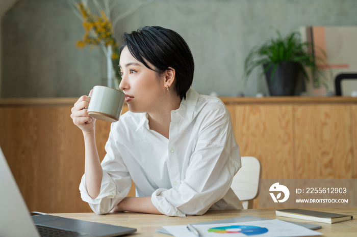 コーヒーを飲みながらリモートワークをする女性