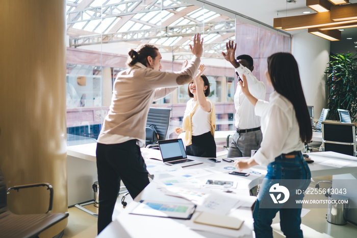 Emotional multiracial team of employees satisfied with productive teamwork and brainstorming session