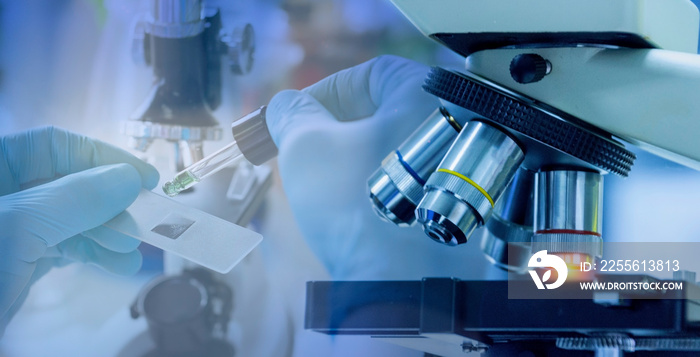 Close up shot of microscope equipment with metal lens in laboratory. Researcher hands in rubber glov