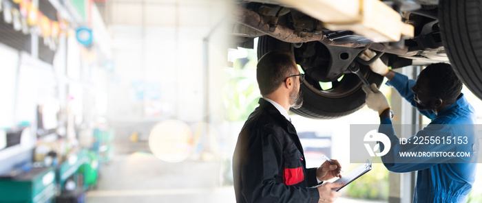 Black man mechanic talking to caucasian manager Under a Vehicle in a Car Service station. Expertise 