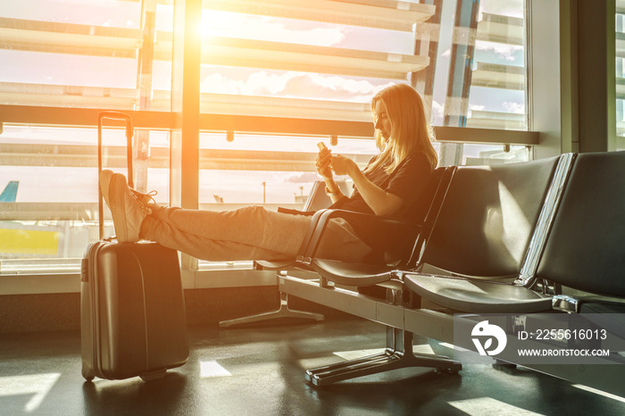 在机场等飞机的女人。年轻的女游客用她的智能手机旅行。Onlin