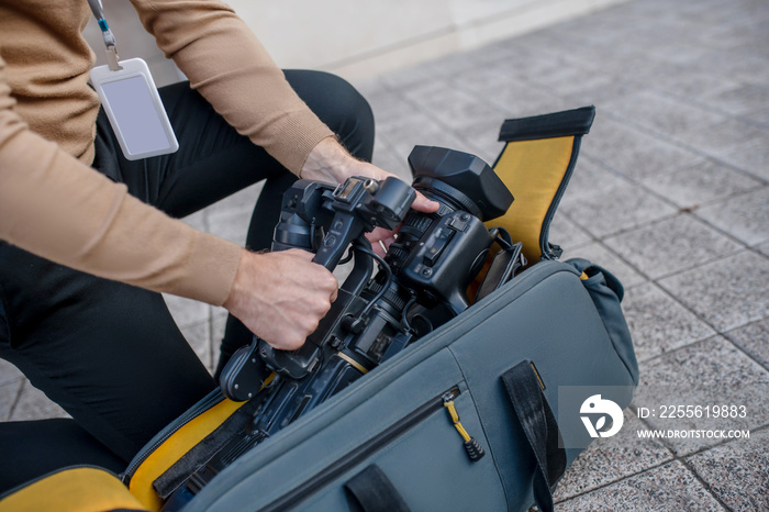 Close-up of operator standing on one knee, taking camera out of the case