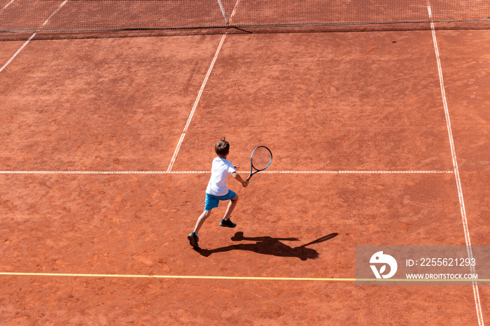 男网球运动员在红土球场上跑短球。俯视图，复制空间。训练，孩子们