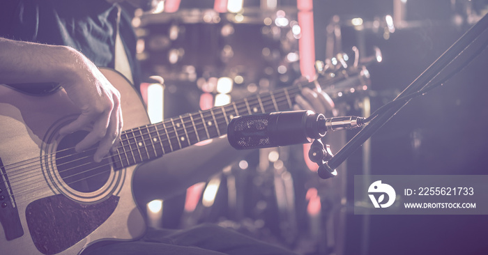 The Studio microphone records an acoustic guitar close-up. Beautiful blurred background of colored l