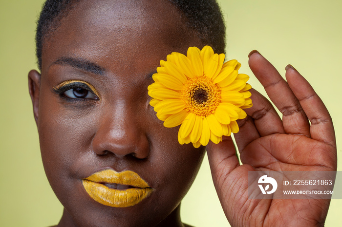 Portrait of woman with yellow lipstick and gerbera