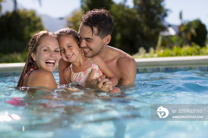 Portrait happy family in sunny swimming pool