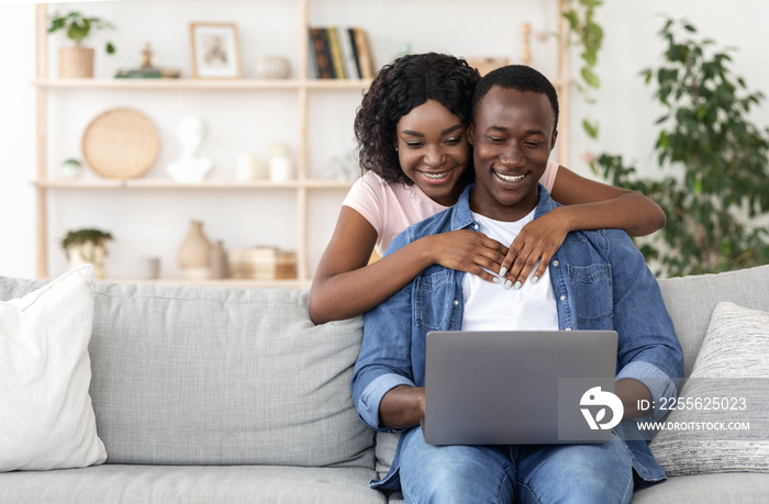 Loving african american couple using laptop together at home