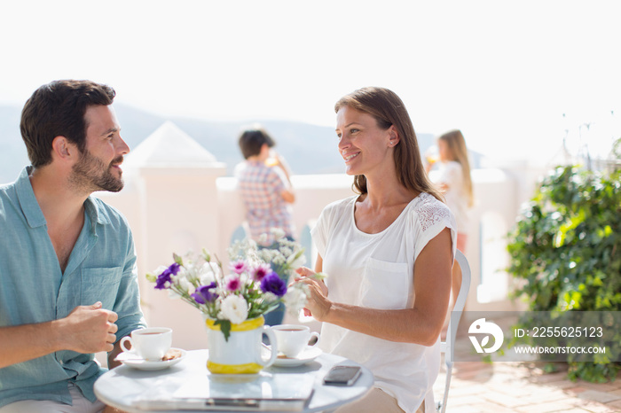 Couple enjoying coffee on sunny balcony