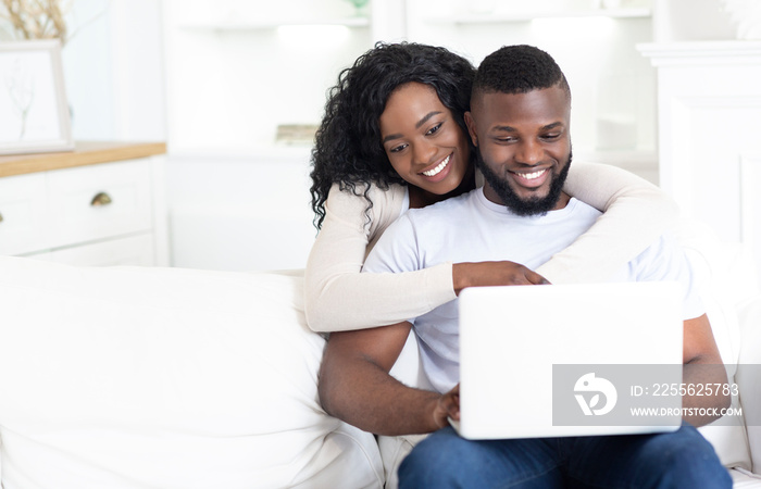 幸福的非裔美国人夫妇在家一起使用笔记本电脑