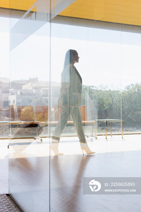 Corporate businesswoman walking in sunny modern office