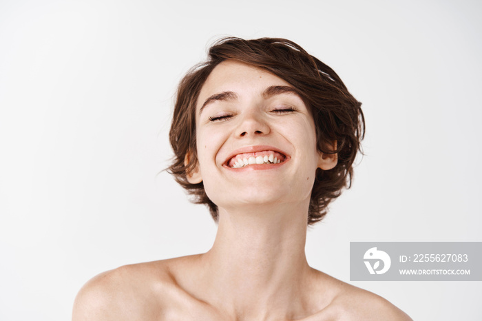 Beauty. Close-up of beautiful and natural girl with white smile and naked shoulders laughing, smilin