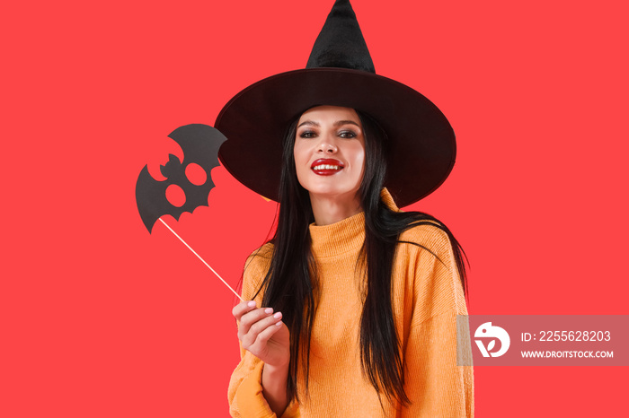 Beautiful young witch with Halloween decor on color background