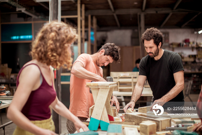 carpenters making wooden objects at workbench in workshop