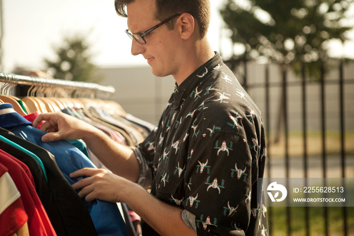 Man choosing shirts at clothes rack