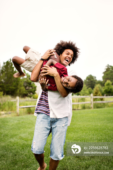 Smiling young man carrying his brother outdoors