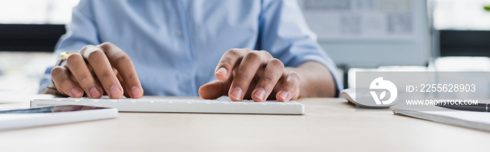 Cropped view of african american businessman using computer keyboard in office, banner