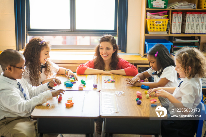 Female teacher helping students (6-7, 8-9) with arts and crafts