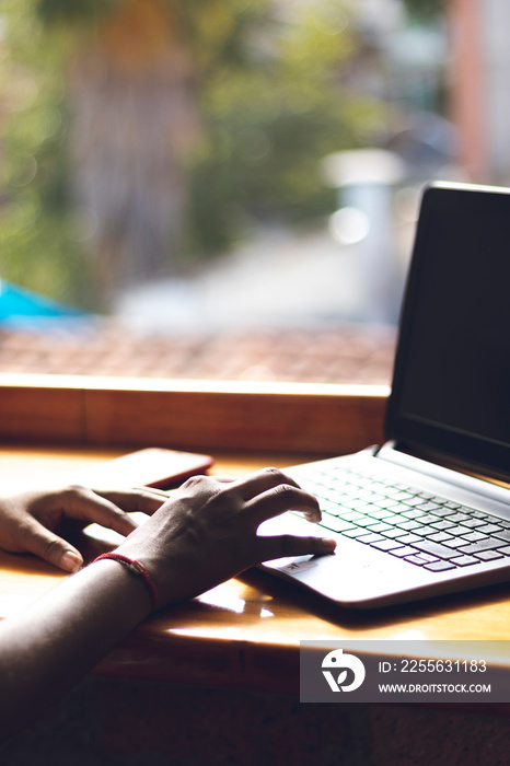 Close-up side view of female fingers typing on laptop keyboard in the meeting room